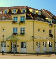 Un edificio giallo con un cartello che recita "HOTEL AM THEATER".