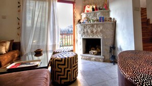 Una sala de estar con sofá, reposapiés, chimenea y vistas al exterior.