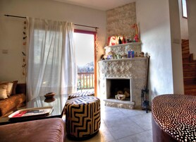 Una sala de estar con sofá, reposapiés, chimenea y vistas al exterior.