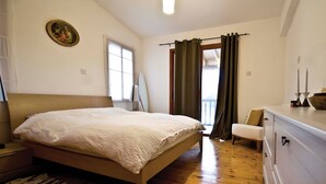 Un dormitorio con una cama de madera, una mesita de noche, una silla, un aparador y una ventana con cortinas.