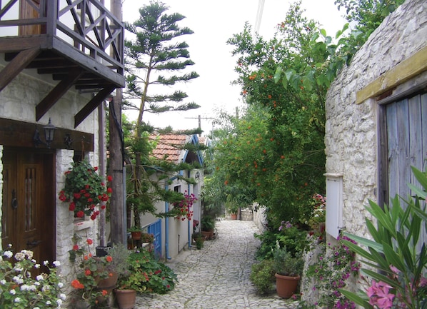 A narrow cobblestone street flanked by buildings with wooden balconies and flower boxes.