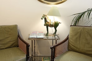 A room with a glass-top table, a lamp, a decorative horse, and two upholstered chairs. - Residenza Cavour (Rome)