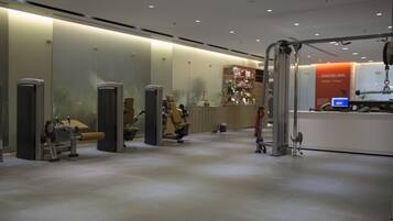 A modern gym with exercise equipment, a reception desk, and a digital kiosk.