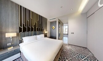 A modern hotel room with a large bed, a decorative wall panel, and a patterned carpet.