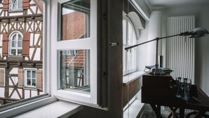 A room with a large window, a desk with a lamp, and a view of traditional buildings outside.