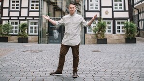 A man standing in front of a traditional half-timbered building with a large glass entrance.