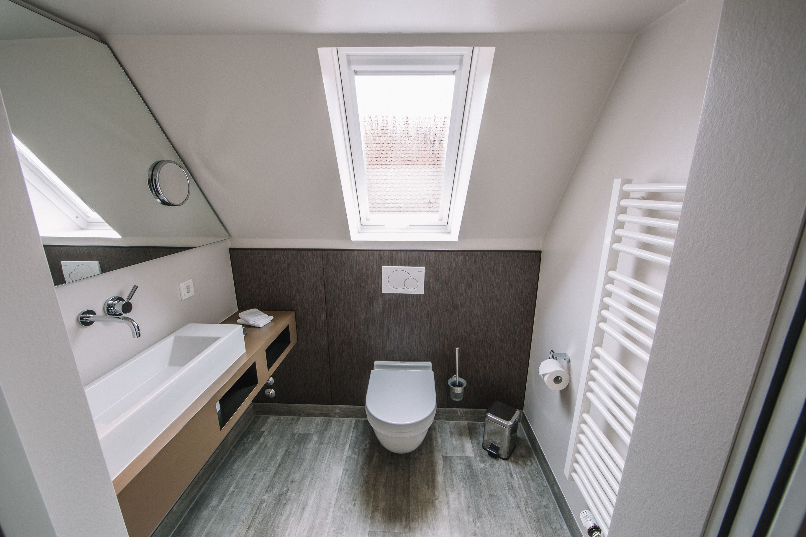 A modern bathroom with a white bathtub, a toilet, and a window above the toilet.