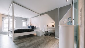 A modern bedroom with a loft bed, a desk, and a chair.