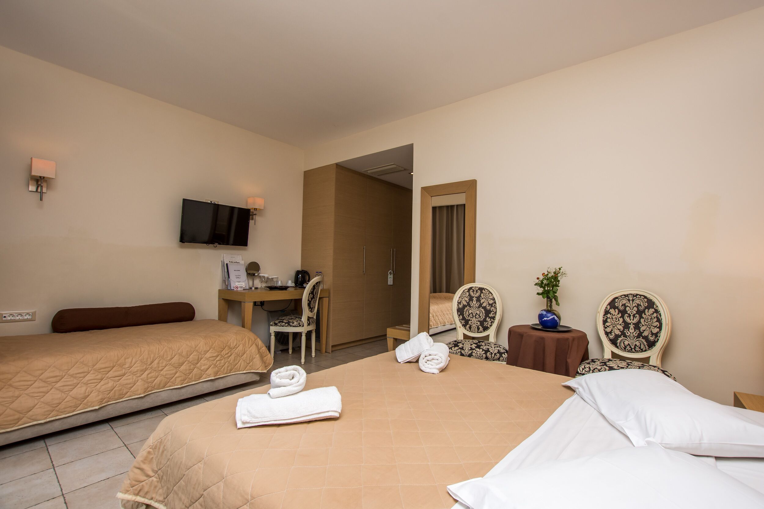A hotel room with two beds, a desk, a TV, and a bathroom.