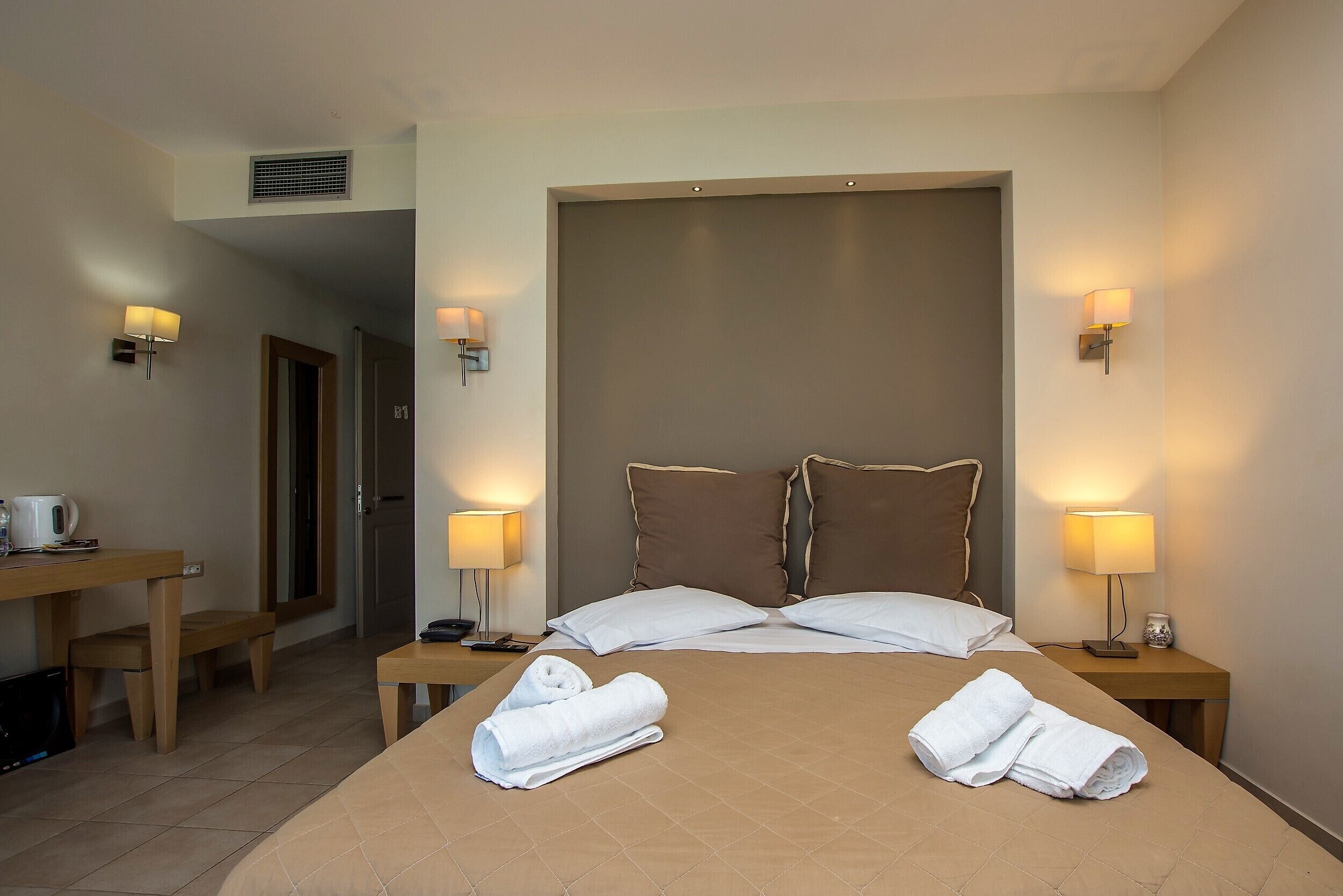 Une chambre d’hôtel avec un grand lit, deux tables de chevet, un bureau et une chaise.