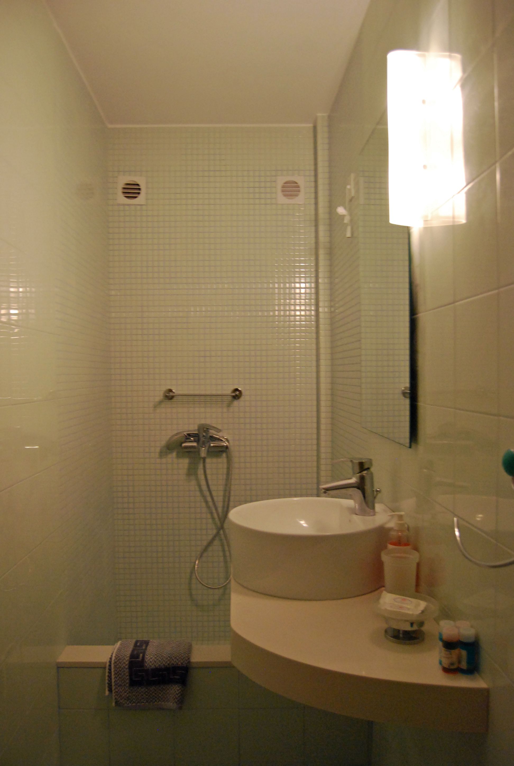 A bathroom with a shower, sink, and mirror.