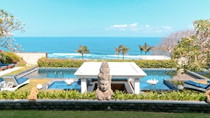 A pool area with a statue, lounge chairs, and a view of the ocean.