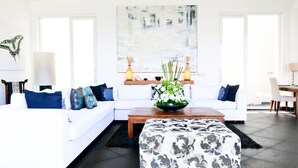 En moderne stue med en hvid sofa, en pyntepude med mønster og et sofabord med blomsterarrangement.