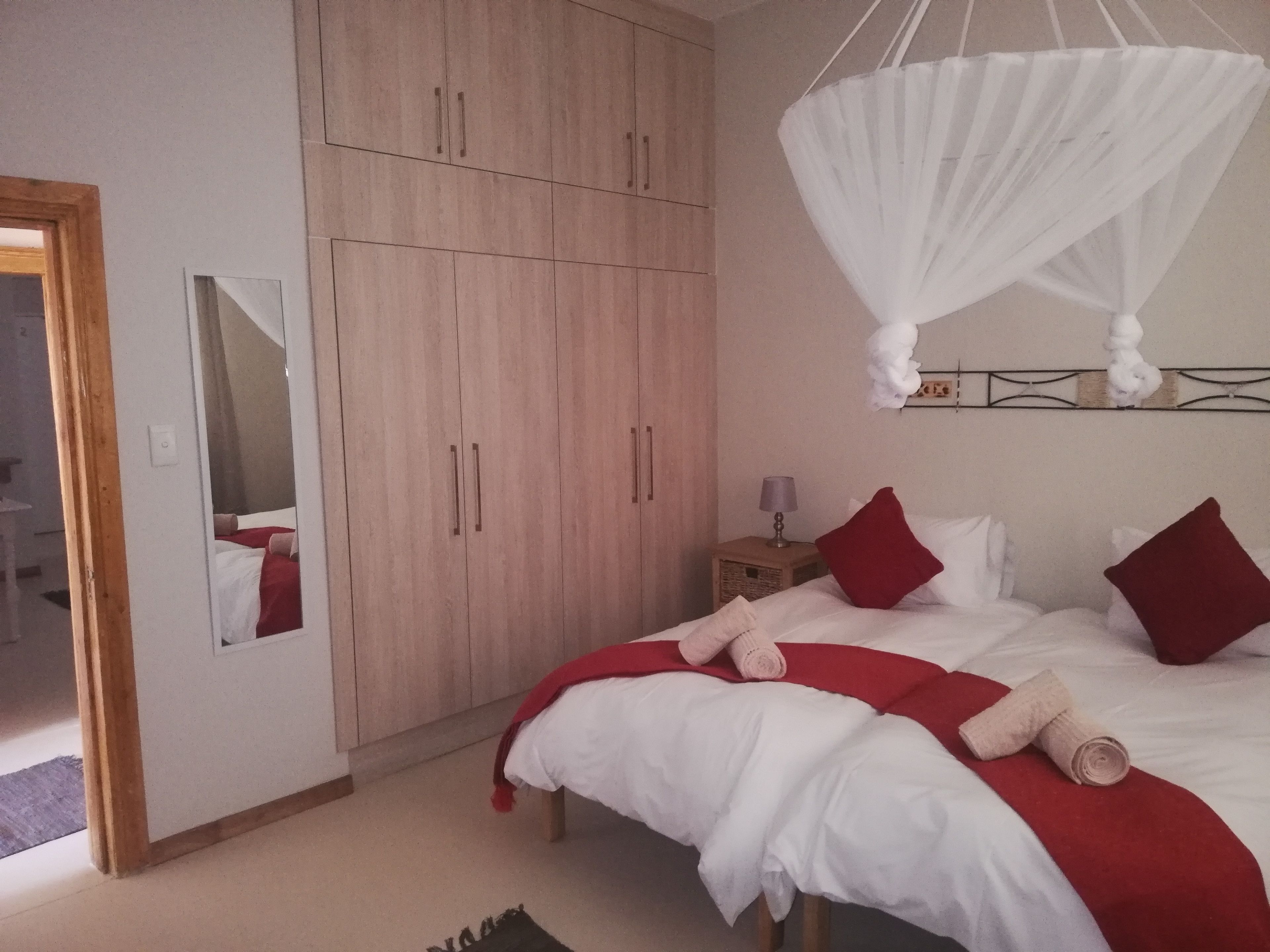 Une chambre à coucher comprenant un lit, une armoire, un miroir et un baldaquin suspendu.