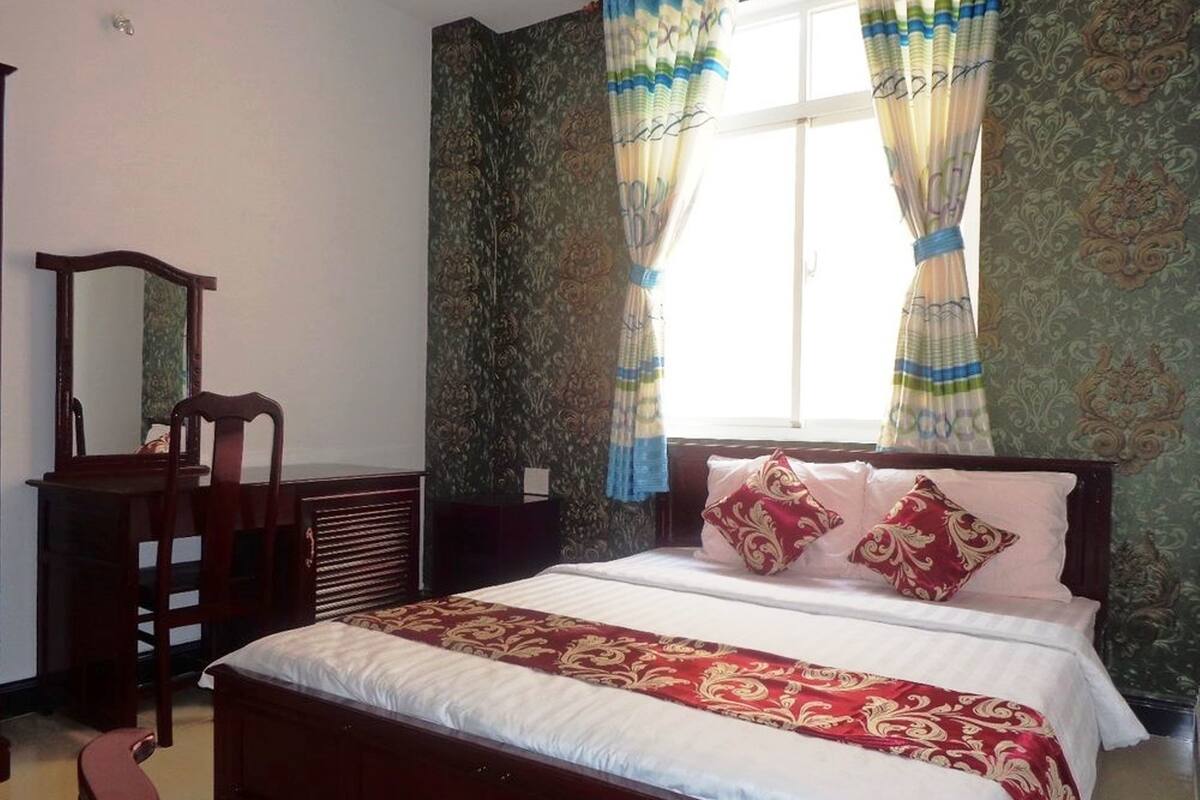 A bedroom with a bed, a dresser, a chair, and a window with curtains.