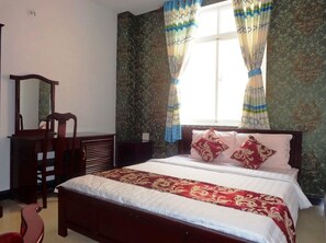 Un dormitorio con cama, cómoda, silla y ventana con cortinas.