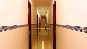 A long, narrow hallway with a reflective floor and a decorative border on the walls. - Thi Long Phung Hotel (Phu Quoc)