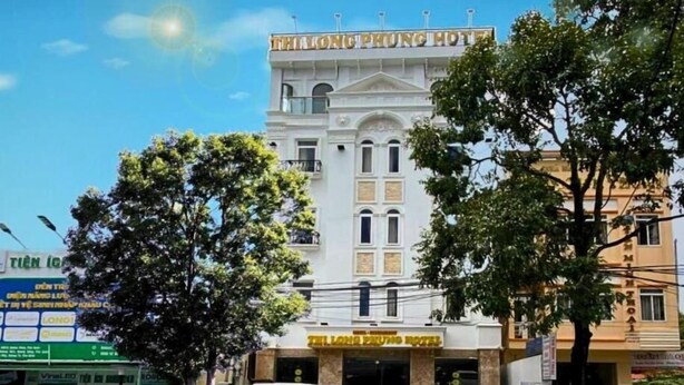 A hotel with a prominent sign reading "THAI LONG PHOENIX HOTEL" and a large entrance with a van and a car parked in front. - Thi Long Phung Hotel (Phu Quoc)
