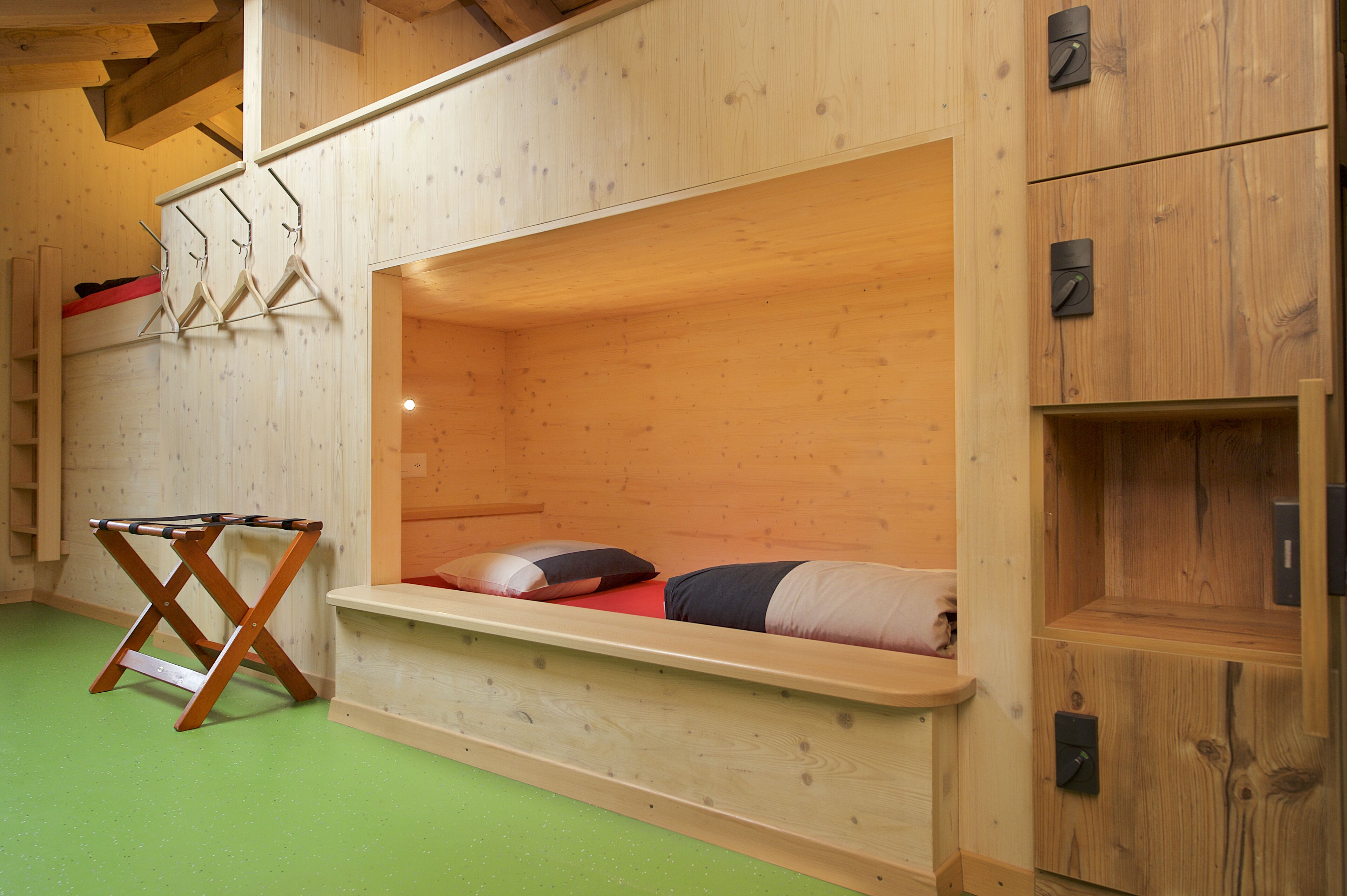 Een houten stapelbed met een klein plankje en een houten bankje.