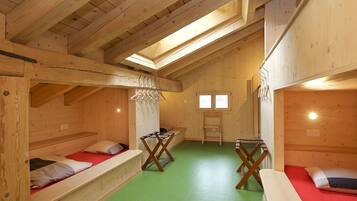 Una cabaña de madera con literas, una mesa pequeña y una ventana.