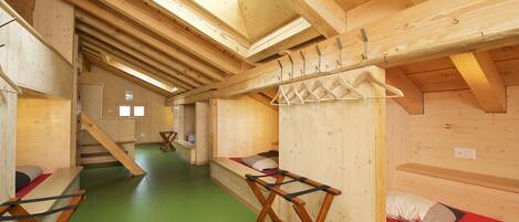 A wooden cabin interior with bunk beds, a staircase, and a green floor.