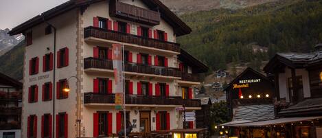 A multi-story hotel with red shutters, a balcony, and a sign for 'Restaurant Rossstall'.