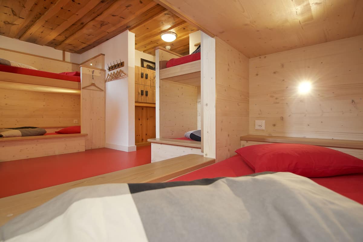 Una cabaña de madera con literas, un armario de madera y una pequeña mesa.