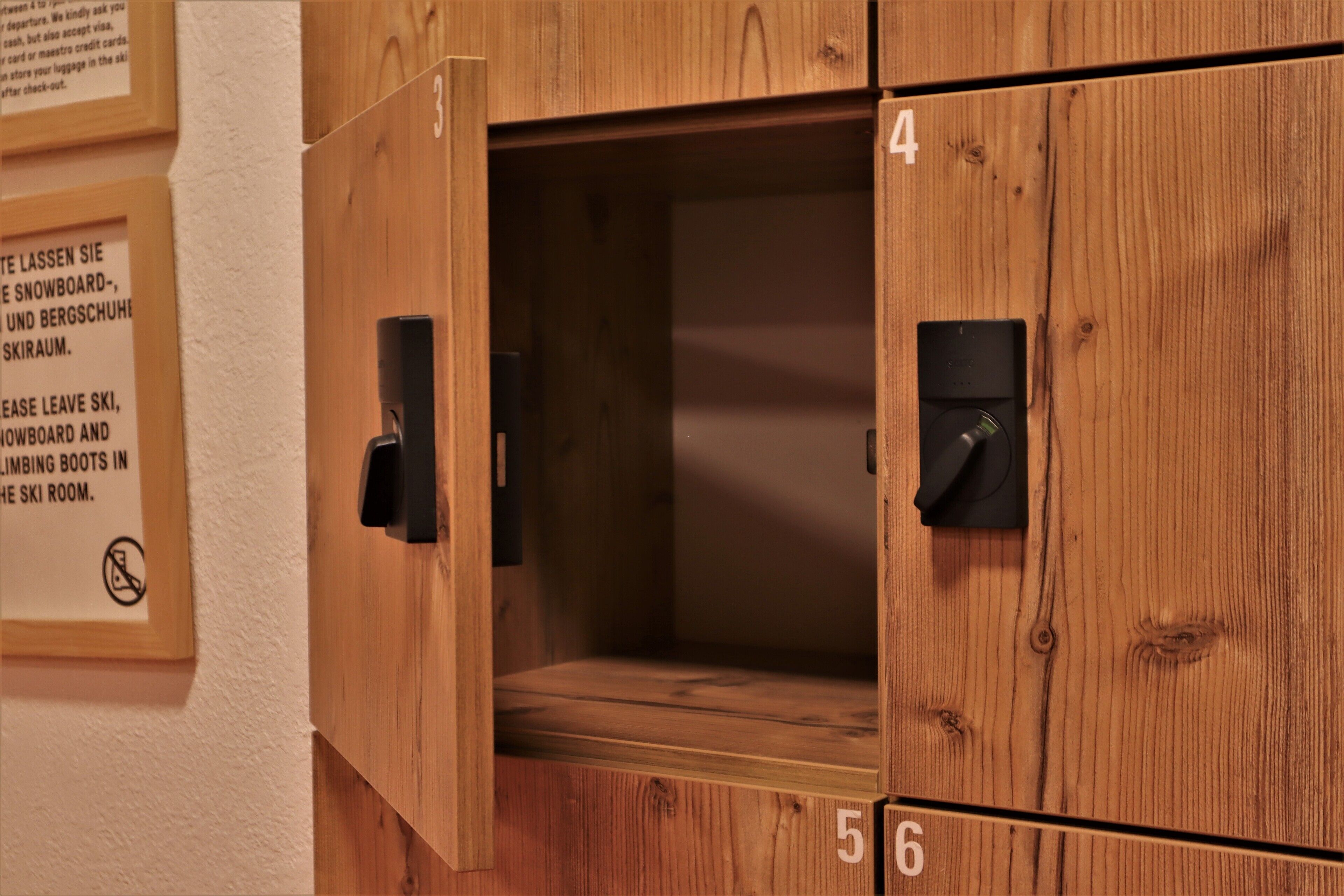 Ein Holzumkleideraum mit nummerierten Schließfächern, einem Hinweisschild und einem Türgriff.