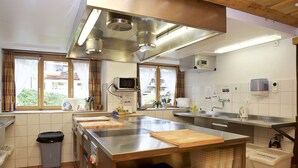 A modern kitchen with stainless steel appliances, a large island, and ample counter space. - Hotel Bahnhof (Zermatt)