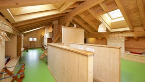 A wooden interior with a sloped ceiling, a green floor, and a small window. - Hotel Bahnhof (Zermatt)