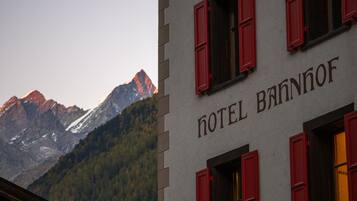 A building with the sign "HOTEL BANNOF" and a mountain view in the background.