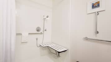 A modern bathroom with a shower, grab bar, and a framed picture on the wall.