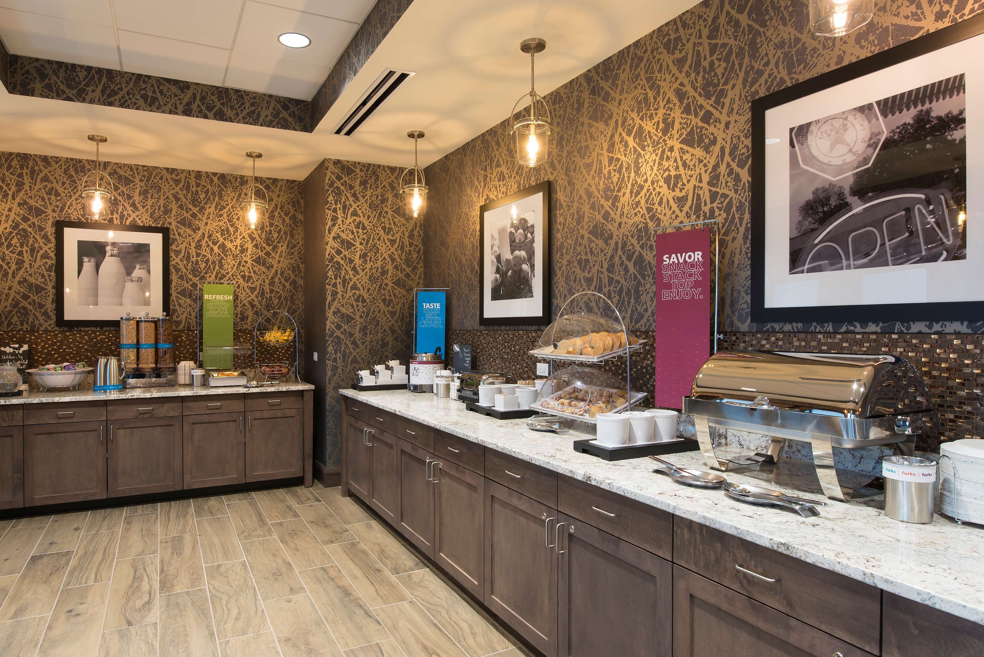 A breakfast bar with a coffee machine, a sandwich display, and various breakfast items.