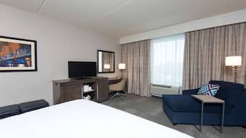 Een hotelkamer met een groot bed, een bureau met stoel, een televisie en een bank.