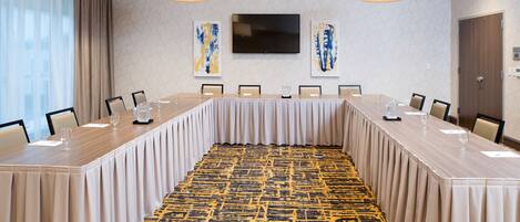A conference room with a long table, chairs, a flat-screen TV, and abstract art on the walls.