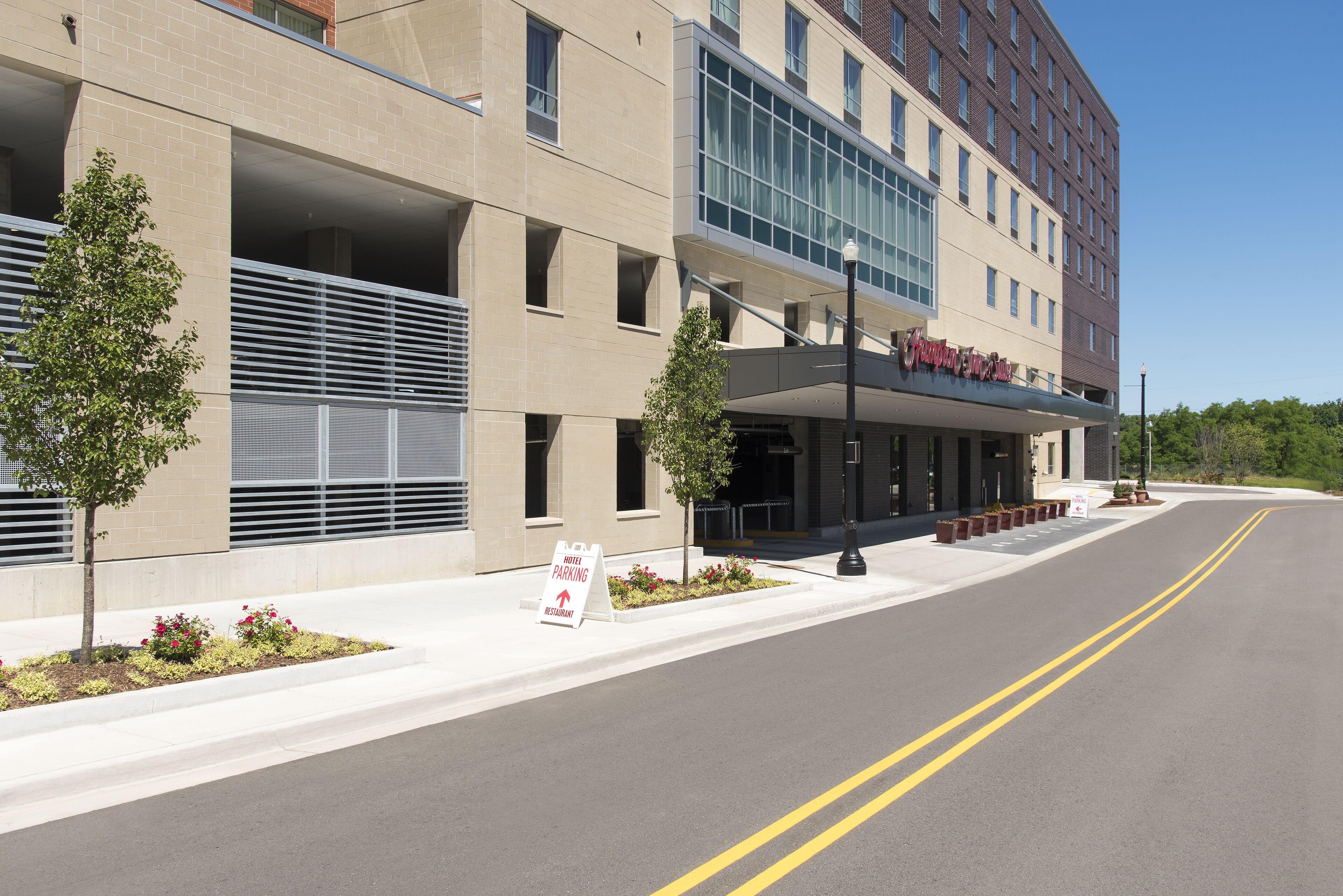 A hotel with a modern facade, a covered entrance, and a clear road in front.