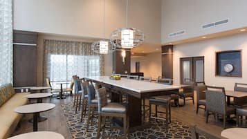 Un lobby moderno de hotel con un amplio comedor, diversas opciones de asiento, incluyendo un bar y una zona de estar.