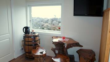 A rustic interior with a wooden barrel, a coffee maker, and a wooden table with a glass of red drink.