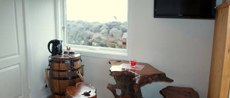 Un interior rústico con un barril de madera, una cafetera y una mesa de madera con una copa de bebida roja.