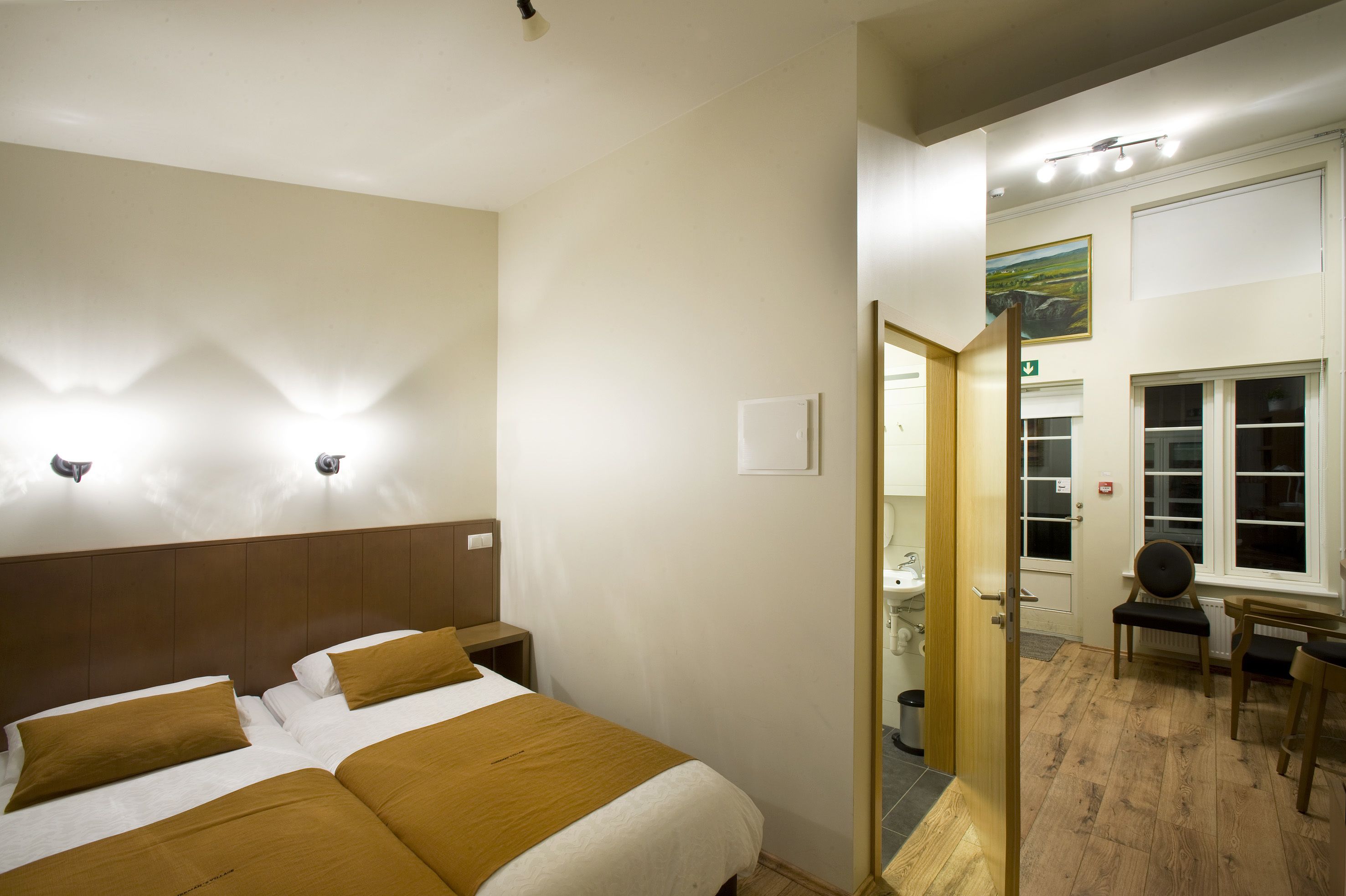 A hotel room with a large bed, a wooden headboard, and a bathroom visible through an open door.