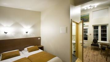 Habitació d'hotel amb un llit gran, un panell de fusta al capçal i un bany visible a través d'una porta oberta.