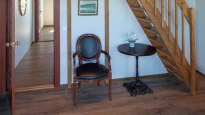 Una escalera de madera con una silla y una mesa en una habitación con piso de madera y techo alto.