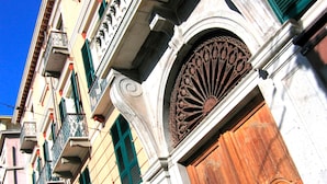 A building with a large wooden door, green shutters, and ornate metalwork. - Ca' del Sol (Cagliari)