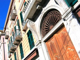 Un edificio con un'ampia porta in legno, persiane verdi e decorazioni in metallo lavorato.