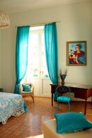 Una stanza con un letto, una scrivania, una sedia e un quadro appeso al muro.