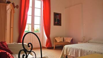 A bedroom with a bed, a chair, a wardrobe, and a window with curtains.