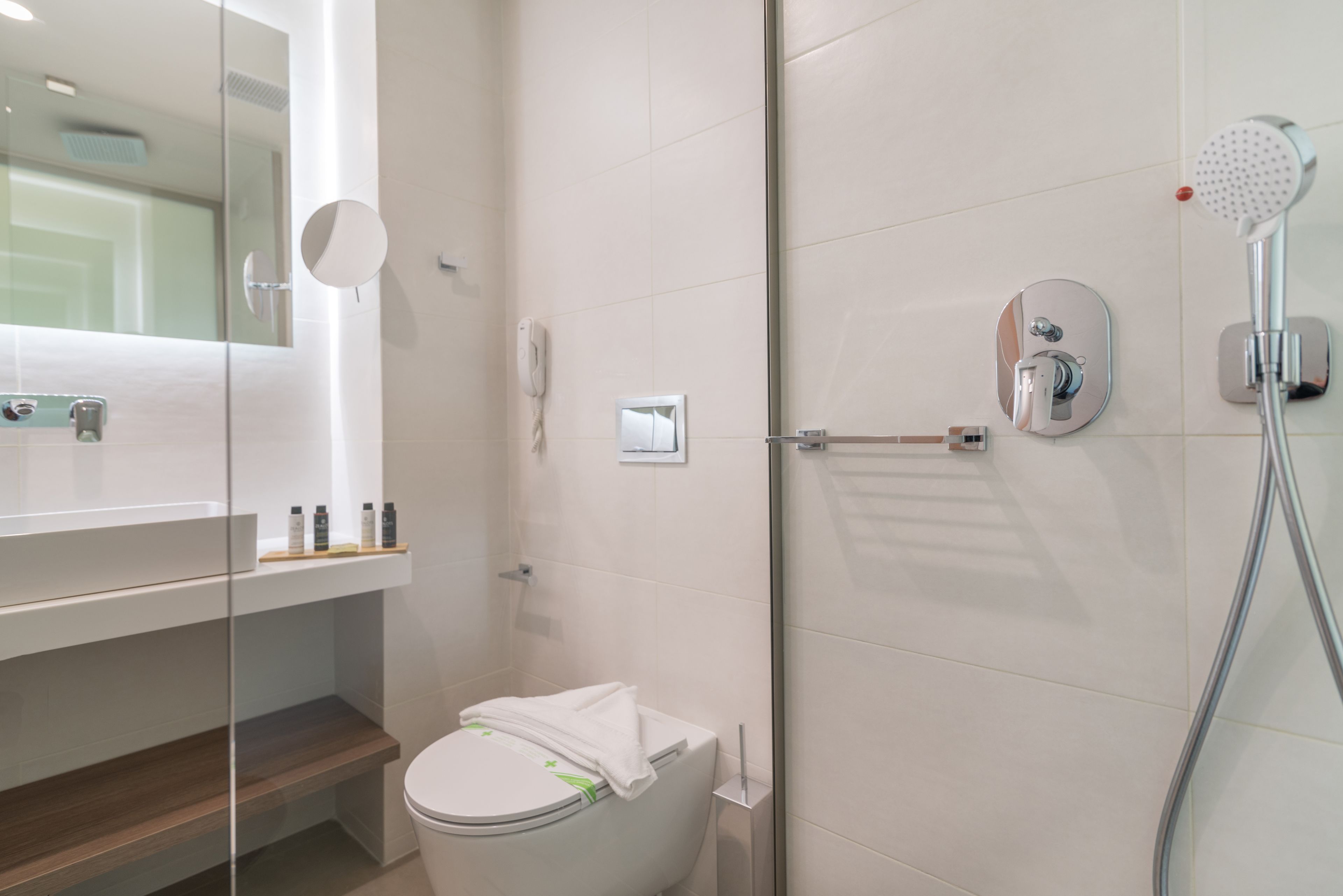 A modern bathroom with a toilet, a glass shower enclosure, and a mirror.