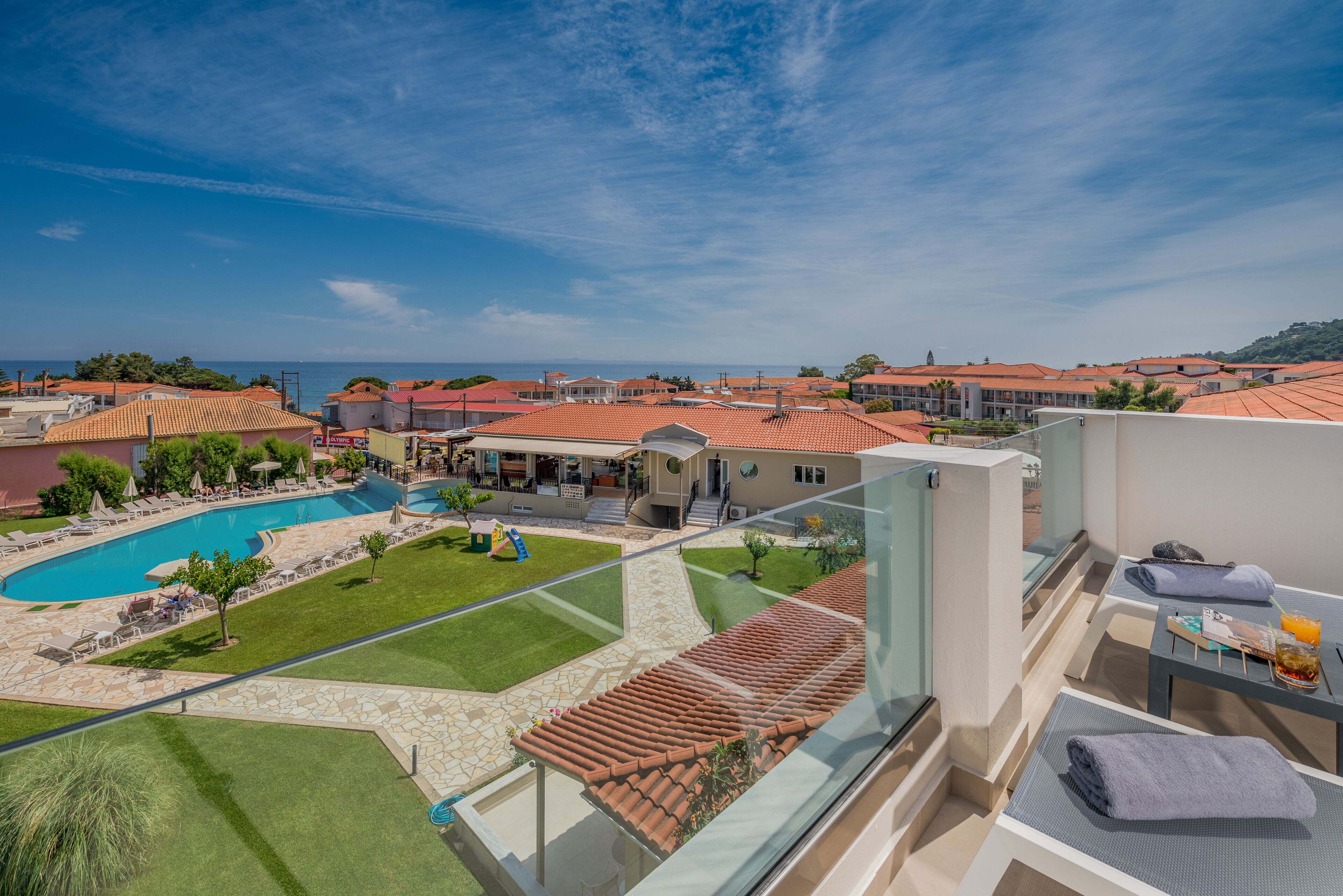 A hotel with a swimming pool, outdoor seating, and a view of the sea.