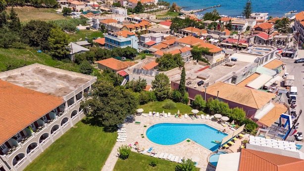 Vista aérea de un pueblo costero con una piscina central rodeada de edificios con tejados rojos.