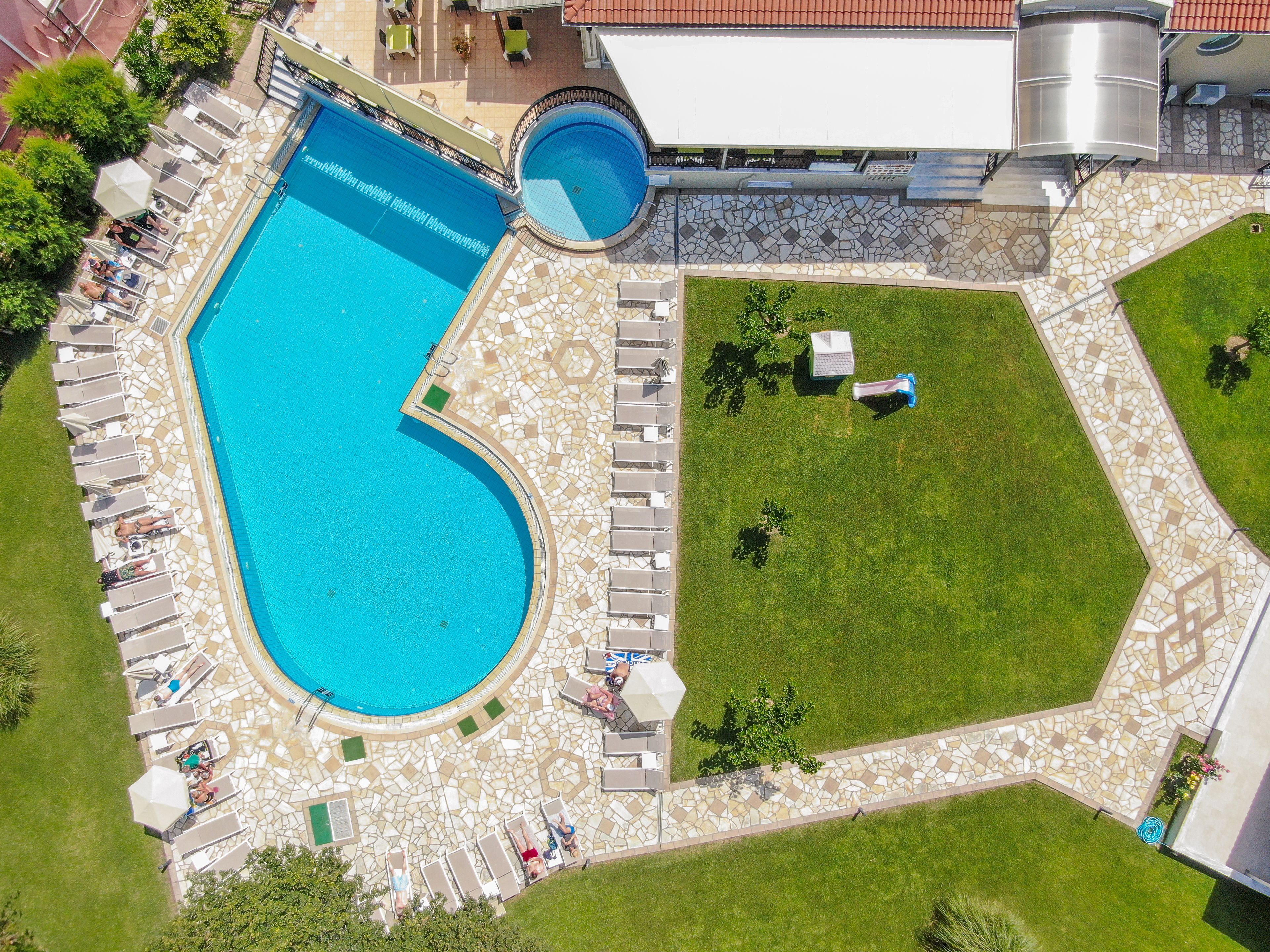 A swimming pool with a heart-shaped design, surrounded by lounge chairs and a stone-tiled deck.